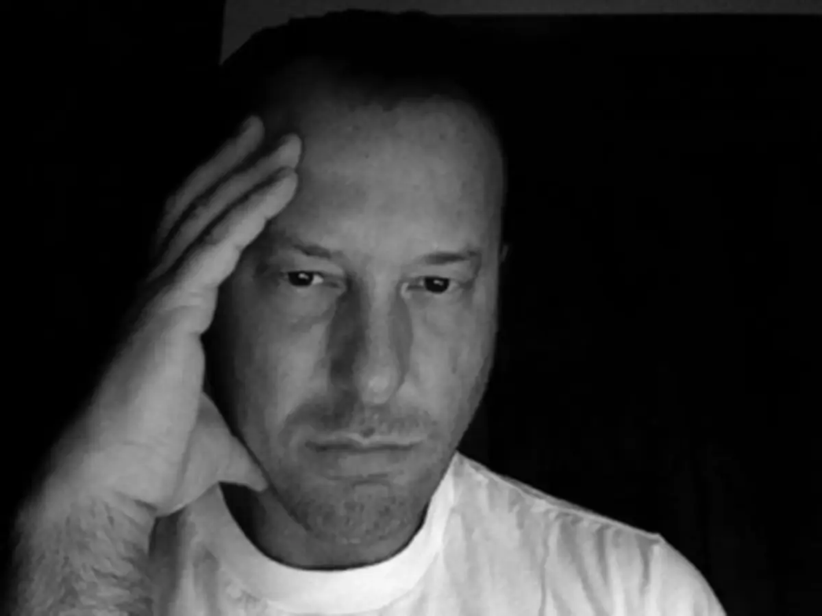 Helmut Lang self-portrait from 2007 showing the Austrian designer in austere black against a stark white wall